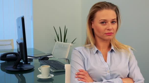 Eine junge, schöne Frau sitzt an einem Schreibtisch in einem Büro, blickt in die Kamera und schüttelt den Kopf — Stockvideo