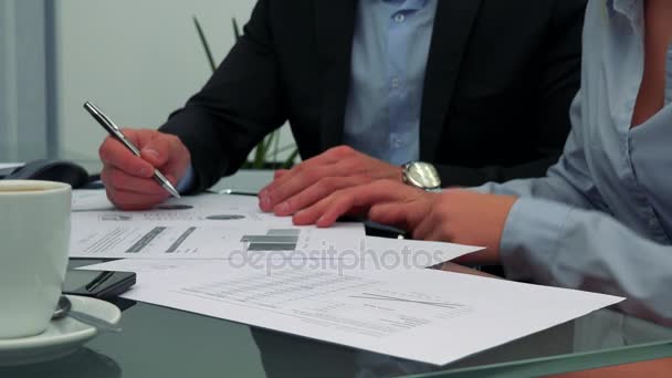 Un hombre y una mujer se sientan en una mesa en una oficina y hacen papeleo. — Vídeo de stock