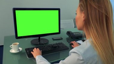 Bir kadın bir ofiste yeşil bir ekran ile bir bilgisayarda çalışıyor