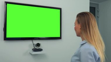 Yeşil televizyon ekranına resmen giyimli bir kadın konuşuyor