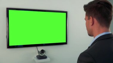 Takım elbiseli bir adam bir yeşil televizyon ekranına görüşmeler