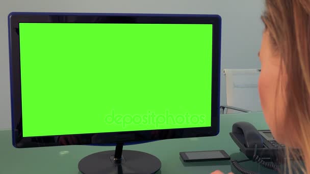 Una mujer escribe en una computadora con una pantalla verde en una oficina — Vídeos de Stock