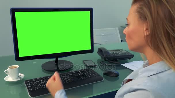 Молодая, красивая женщина сидит перед компьютером с зеленым экраном в офисе, злой — стоковое видео