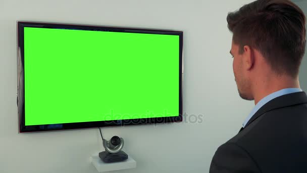 Um homem de fato fala com uma tela de televisão verde — Vídeo de Stock