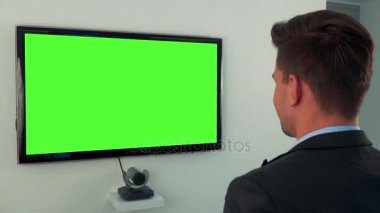 Bir takım elbise dansları yeşil televizyon ekranının önünde bir adam