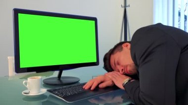 Genç ve yakışıklı bir adam bir yeşil bilgisayar ekranı önünde bir masa üzerine uyur