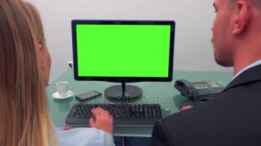 Bir erkek ve bir kadın bir bilgisayar önünde bir ofiste yeşil bir ekran ile konuşuyor ve o türleri oturmak