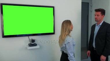 Bir erkek ve bir kadın bir yeşil televizyon ekranı durmak ve konuşmak
