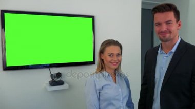 Bir erkek ve bir kadın (genç ve çekici) yeşil televizyon ekranı durmak ve Kameraya gülümse
