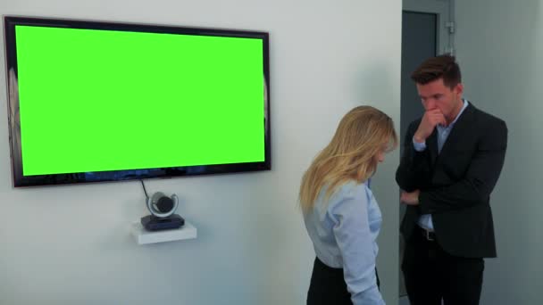 Um homem e uma mulher estão ao lado de uma tela de televisão verde, chateados — Vídeo de Stock