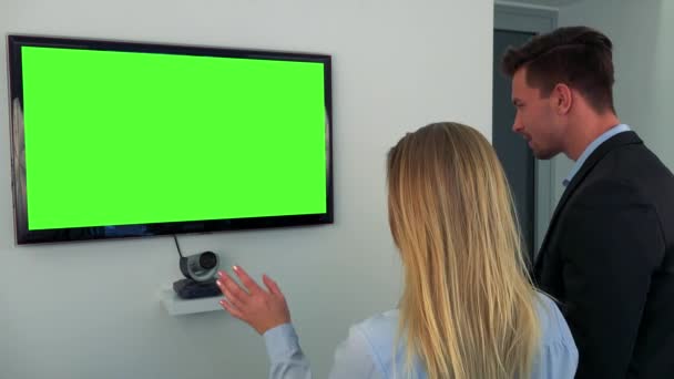 Un hombre y una mujer hablan con una pantalla de televisión verde — Vídeos de Stock