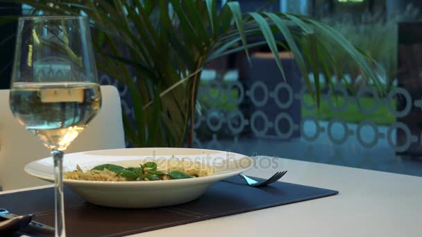 Een bord pasta op een tafel in een restaurant en een glas wijn op de voorgrond — Stockvideo