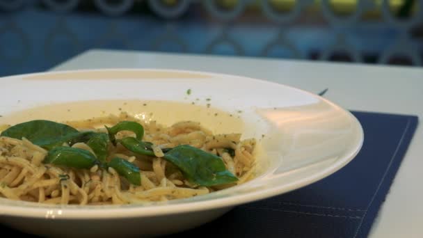 Тарелка макарон с листьями на столе в ресторане - крупный план — стоковое видео
