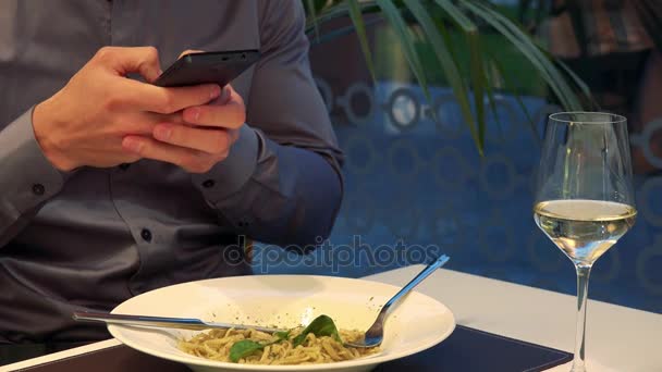 Bir adam bir restoranda bir masada oturur ve yemeğini bir akıllı telefon ile bir fotoğraf çeker — Stok video