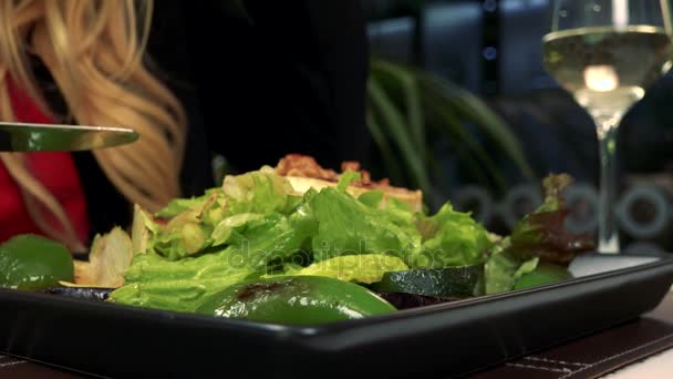 Una mujer come una ensalada en un restaurante - primer plano en el plato — Vídeos de Stock