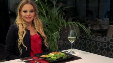 Genç, güzel bir kadın bir restoran ve kamera, onun önünde bir salata gülümser bir masada oturur