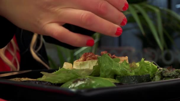 Una mujer echa sal a una ensalada en un restaurante - primer plano — Vídeo de stock