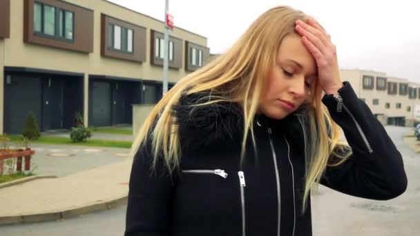 Een mooie, jonge vrouw staat op de straat in een voorstedelijk gebied en geeft teleurstelling en woede — Stockvideo