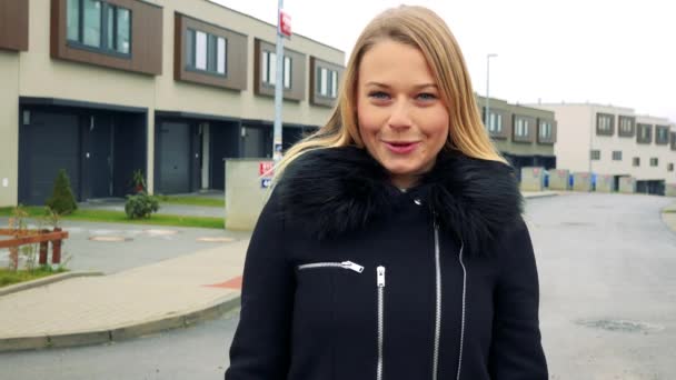 Una joven y hermosa mujer se para en la calle en una zona suburbana y habla con la cámara — Vídeos de Stock