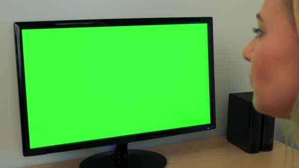 Una mujer joven se sienta en un escritorio y trabaja en un ordenador con una pantalla verde - primer plano — Vídeo de stock