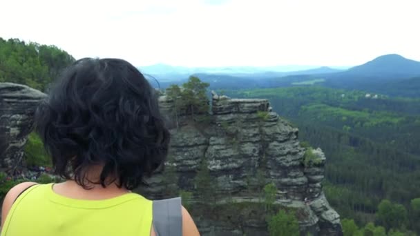 Una donna (dietro la testa alla macchina fotografica) gode di una vista in una foresta e una roccia — Video Stock