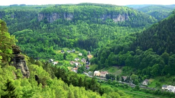 En by som medföljer en skog och klippor - ovanifrån — Stockvideo