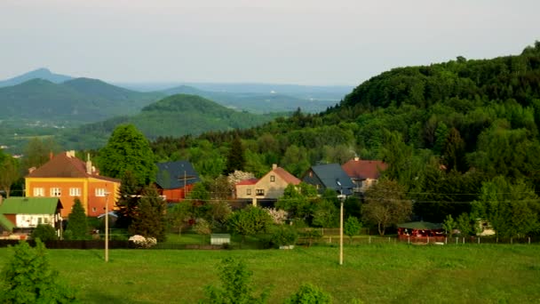 A village - a meadow in the foreground, a mountainious landscape in the background — Stock Video