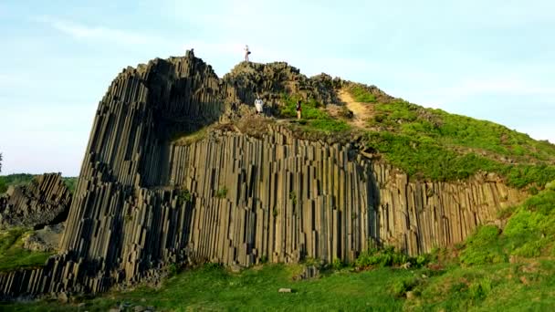 Una roca de basalto columnar, un excursionista en su parte superior y el cielo azul brillante en el fondo — Vídeo de stock