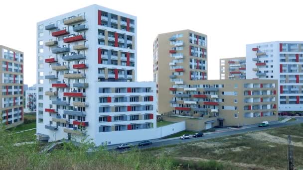 Edifícios de apartamentos coloridos esparsos em uma área urbana, uma estrada e vegetação baixa em primeiro plano, o céu brilhante no fundo vista superior — Vídeo de Stock