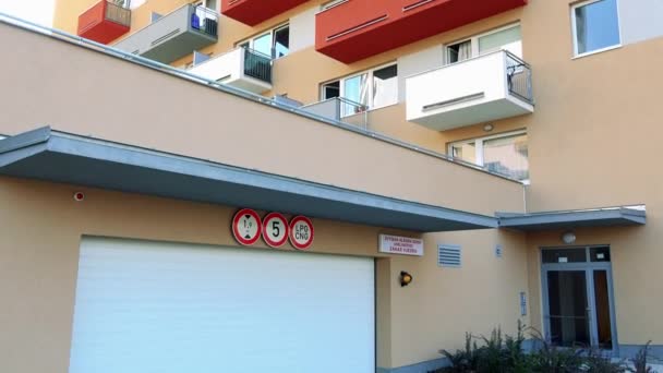 Ein Eingang und ein Garagentor eines beigefarbenen Mehrfamilienhauses mit bunten Balkonen in einem städtischen Gebiet — Stockvideo