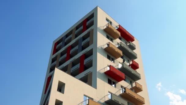 The top of a colorful apartment building in an urban area, the blue sky with sparse white clouds in the background — Stock Video