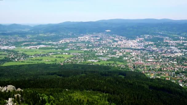 Una pequeña ciudad rodeada por un bosque, el cielo azul en el fondo - vista superior — Vídeo de stock