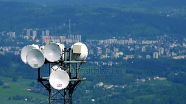 Üst kısmında bir radyo kulesinden, bir kasaba ve bir ormanda bulanık arka plan beyaz parabolik antenler