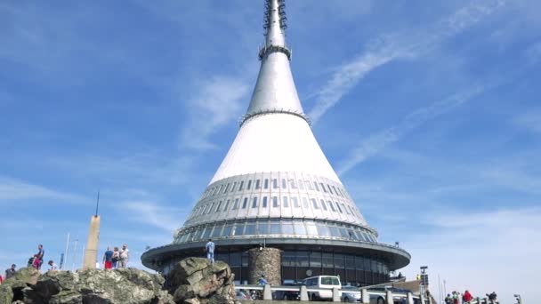 Oamenii merg în jurul unui turn de televiziune alb, cerul albastru strălucitor în fundal — Videoclip de stoc