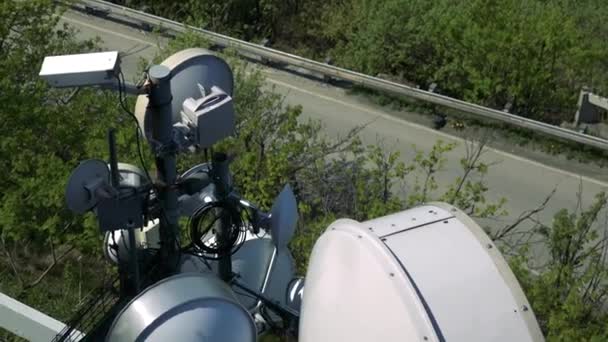 Antenne paraboliche su ringhiera, alberi e una strada sotto - vista dall'alto — Video Stock