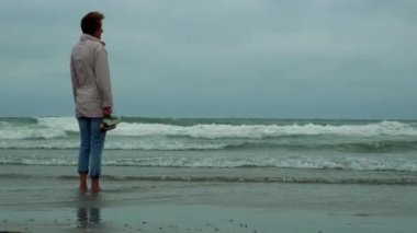 Bir kadın bir kumsalda yalınayak durumda 