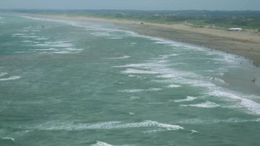 Çalkantılı deniz yüzeyi etrafında bir plaj 