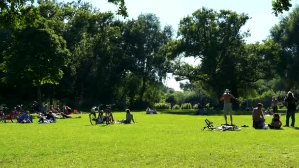 As pessoas sentam-se e caminham no parque — Vídeo de Stock