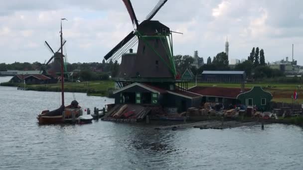 Люди идут на ветряную мельницу у реки — стоковое видео