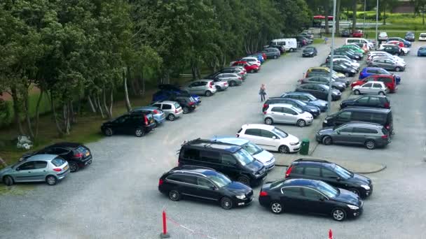 As pessoas andam e um carro dirige em um parque de estacionamento — Vídeo de Stock