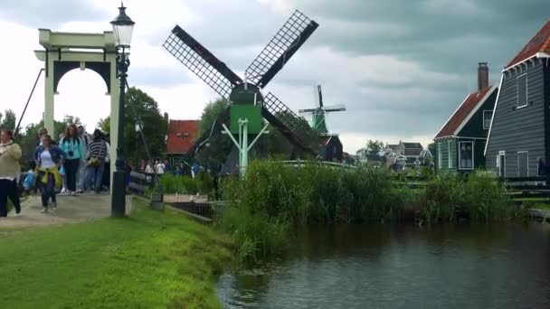 Brug over een rivier door een windmolen in een kleurrijk dorp — Stockvideo