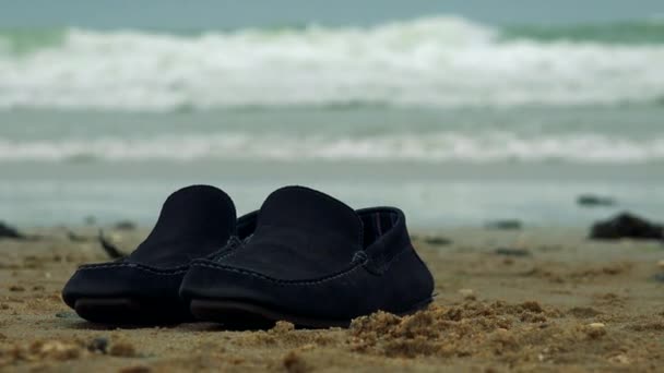 Zapatos negros en una playa — Vídeo de stock