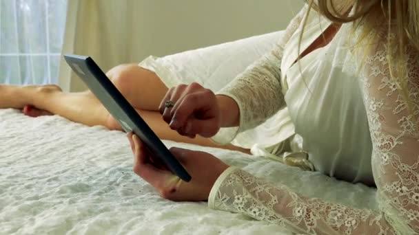 Frau liegt im Bett und arbeitet an einem Tablet — Stockvideo