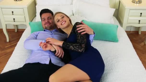 Un hombre y una mujer caen en una cama mientras sonríen — Vídeo de stock