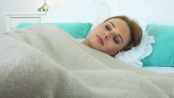 Een jonge aantrekkelijke vrouw slaapt in een bed — Stockvideo