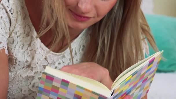 Frau liegt auf einem Bett und liest ein Buch — Stockvideo