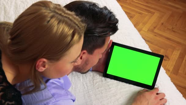Um casal está em uma cama e olha para um tablet — Vídeo de Stock