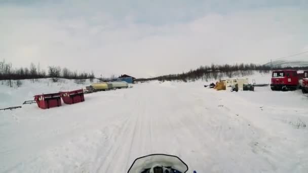 El hombre conduce la moto de nieve en el pequeño pueblo — Vídeo de stock