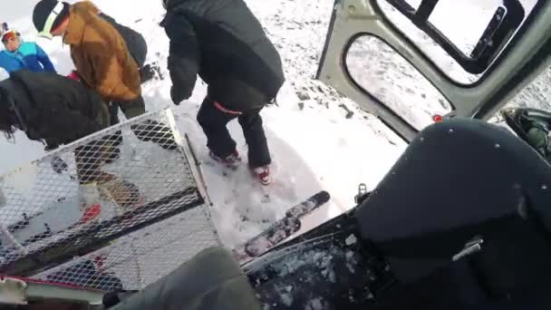 Man skiër komt uit de helikopter met vrienden — Stockvideo