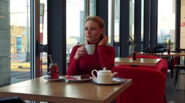 kadın çay içiyor ve kafede bir pencereden dışarı bakar